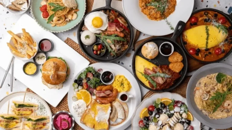 Flatlay of traditional American dishes including pancakes, omelets, burgers, sandwiches, pasta, and fresh fruits