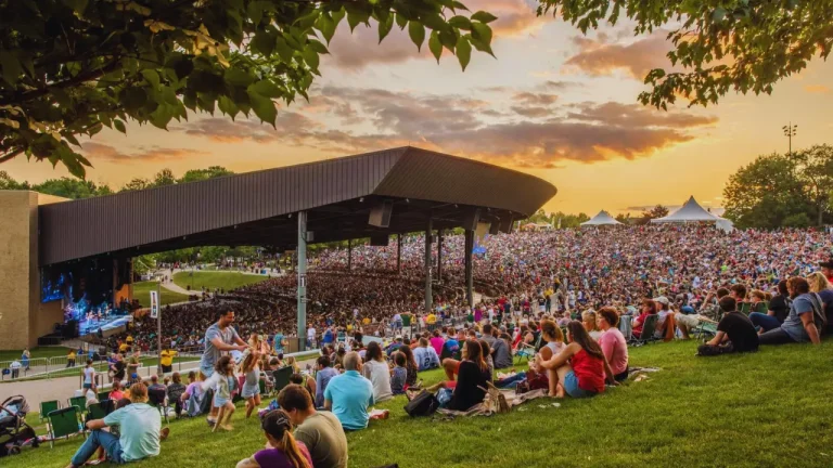Large crowd enjoying a live outdoor concert at Bethel Woods Center for the Arts in New York during sunset